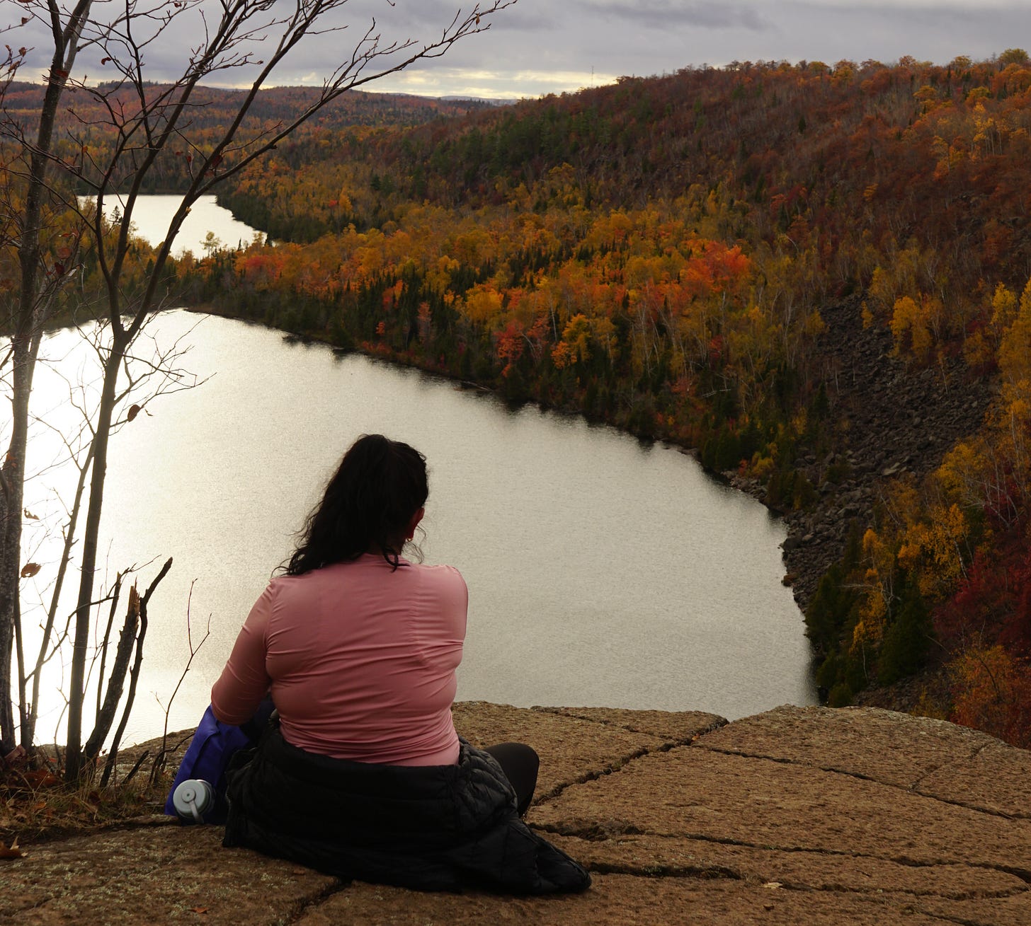 My friend sitting on a cliff overlooking two lakes at sunset as colors of red, orange, and yellow illuminate around the shadows. My friend sitting on a cliff overlooking two lakes at sunset as colors of red, orange, and yellow illuminate around the shadows.