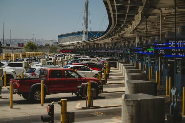 Vehicles lined up in a long row of lanes between booths. Vehicles lined up in a long row of lanes between booths.