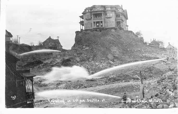 a house stands above the surrounding area on a fragment of hill, while water cannons spray