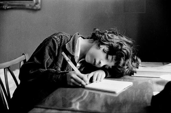 This may contain: a woman laying on top of a wooden table next to a desk with a pen and paper