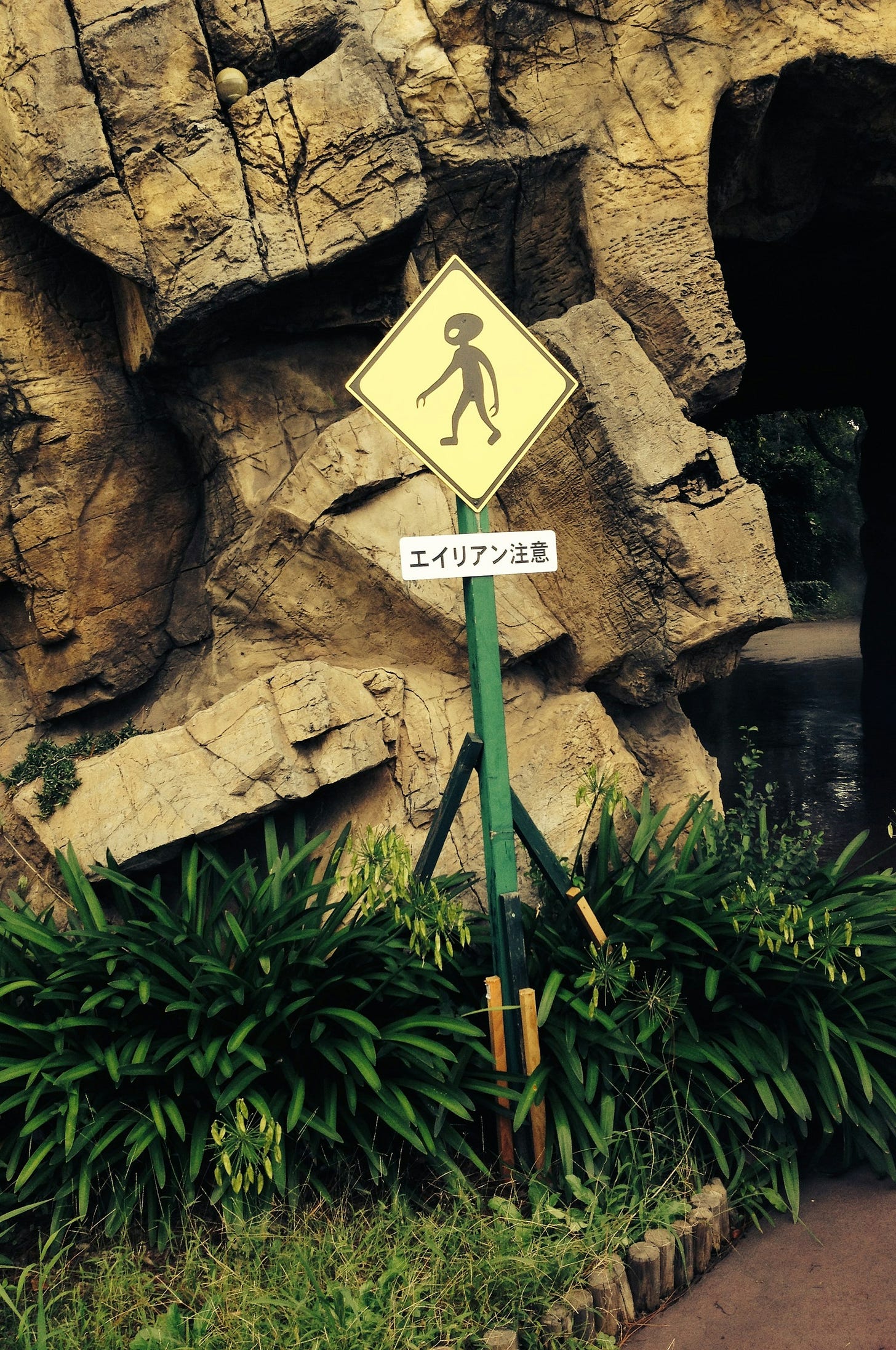 a road sign with an extraterrestrial against a rock roadside embankment a road sign with an extraterrestrial against a rock roadside embankment