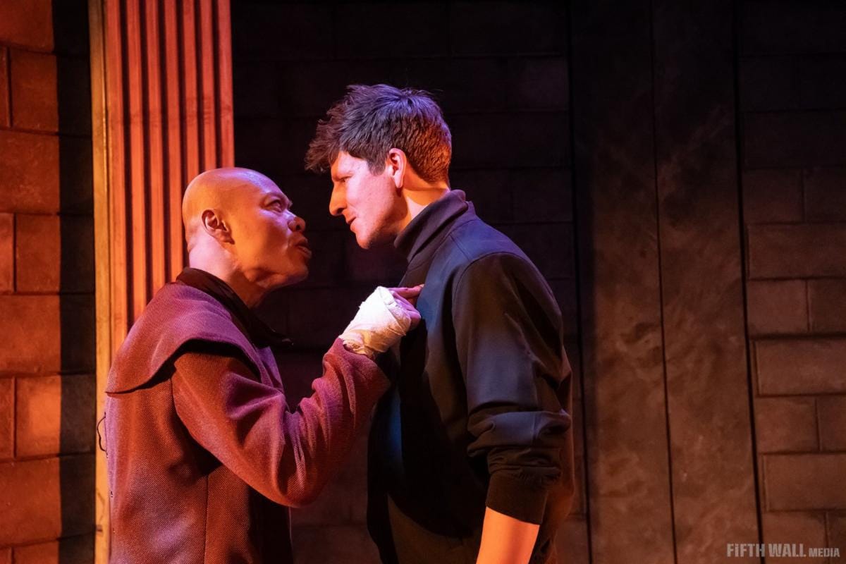 Mike Tan, dressed as a monk, pokes his finger into Matthew McKinney's chest.