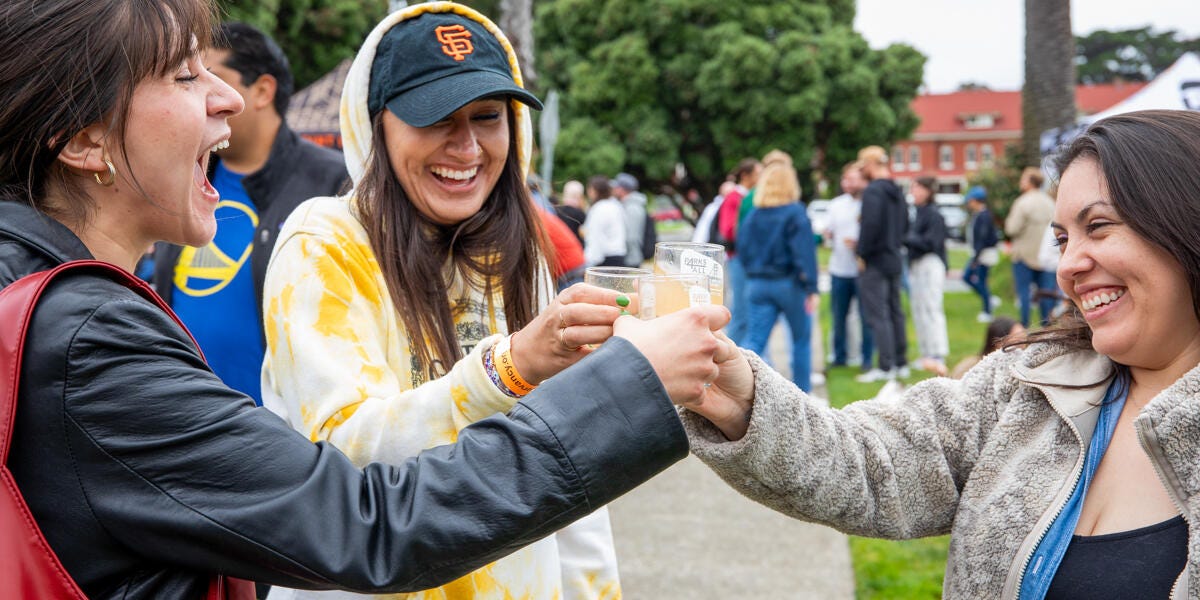 Three smiling and laughing women raise their glasses at the Parks4All: Brewfest in the Presidio Three smiling and laughing women raise their glasses at the Parks4All: Brewfest in the Presidio