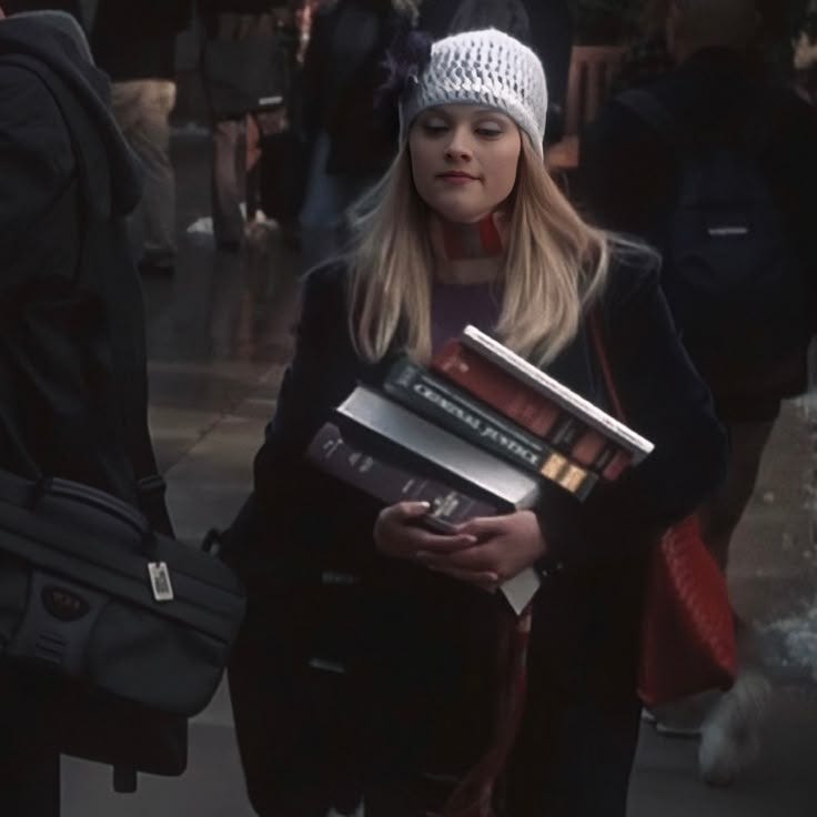 This may contain: a woman is carrying books in her hands