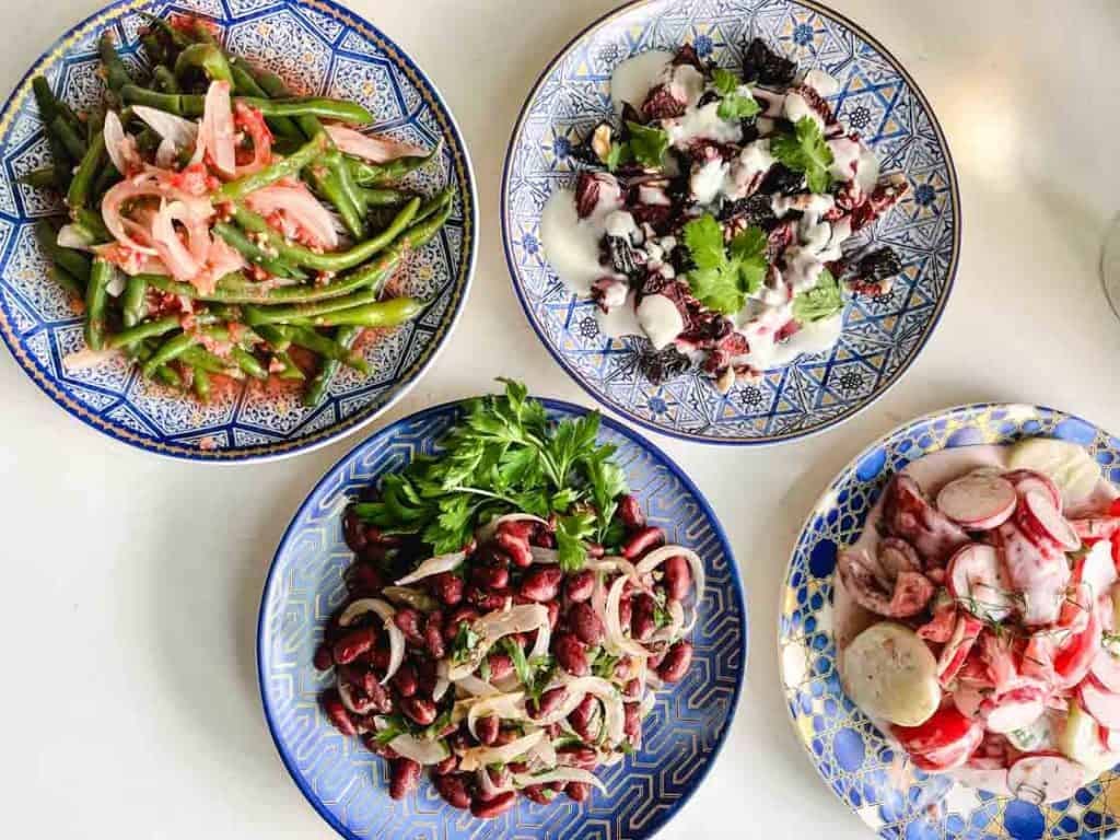 overhead shot of 4 Ukrainian salads on blue and gold round plates overhead shot of 4 Ukrainian salads on blue and gold round plates