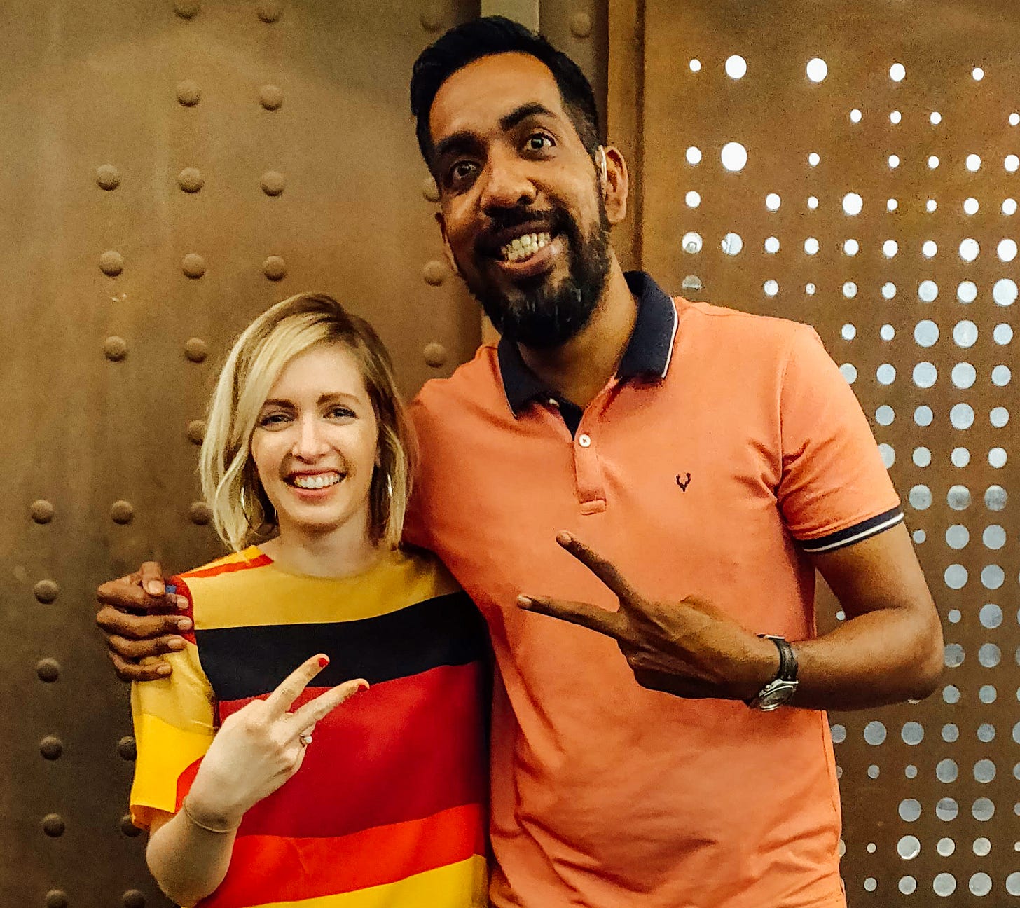 Prasanna and I in Bangalore, wearing orange tshirts, smiling, and giving a peace sign with our hands