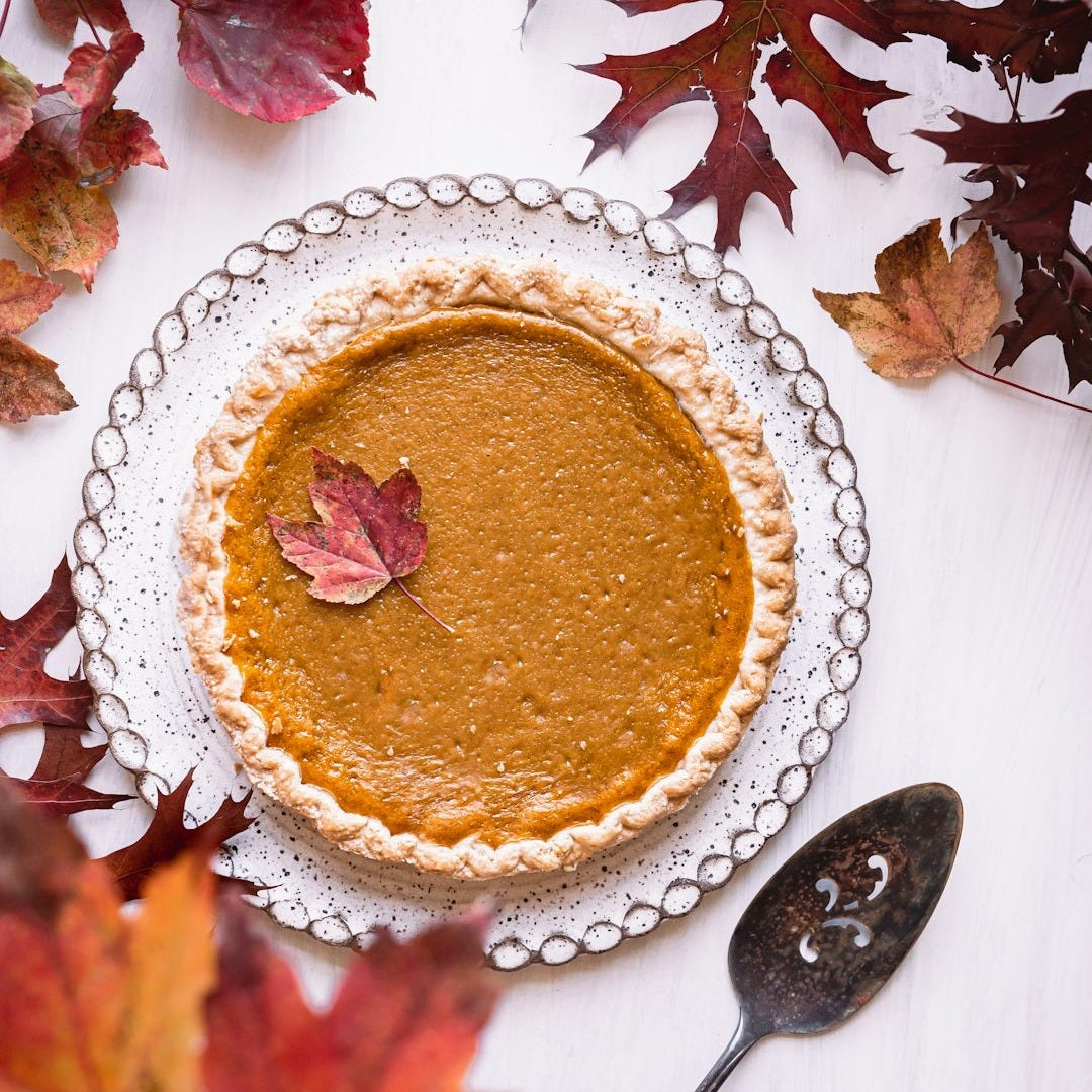 a pie sitting on top of a white table next to leaves
