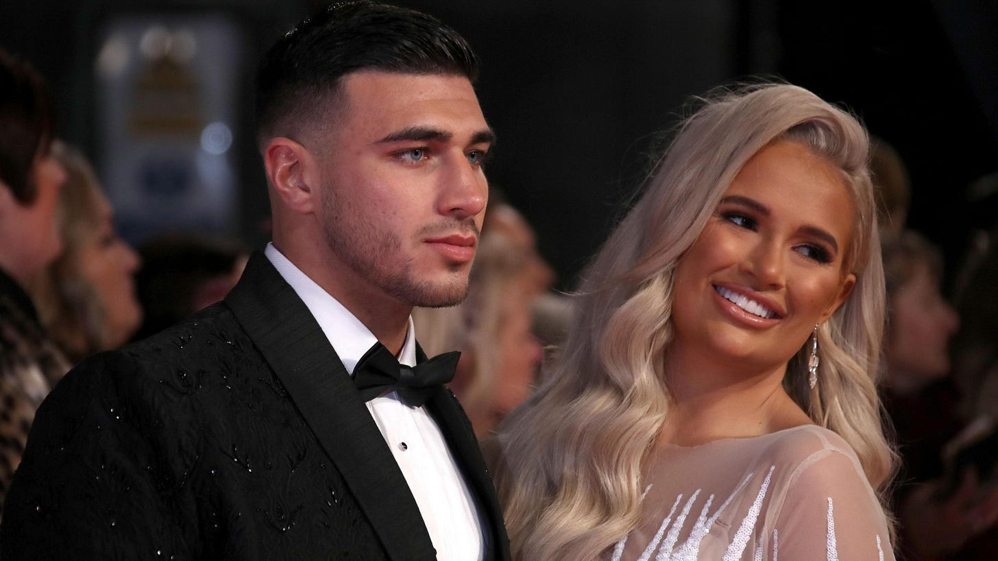 Tommy Fury in a black suit and Molly-Mae Hague in a light coloured dress Tommy Fury in a black suit and Molly-Mae Hague in a light coloured dress