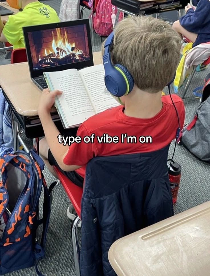 This may contain: a young boy sitting at a desk with headphones on while using a laptop computer