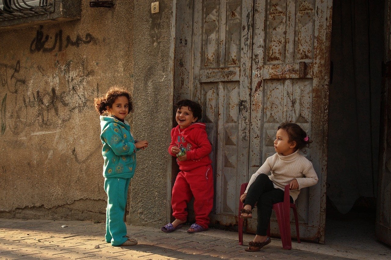 Three children in front of door next to wall with graffiti. Three children in front of door next to wall with graffiti.