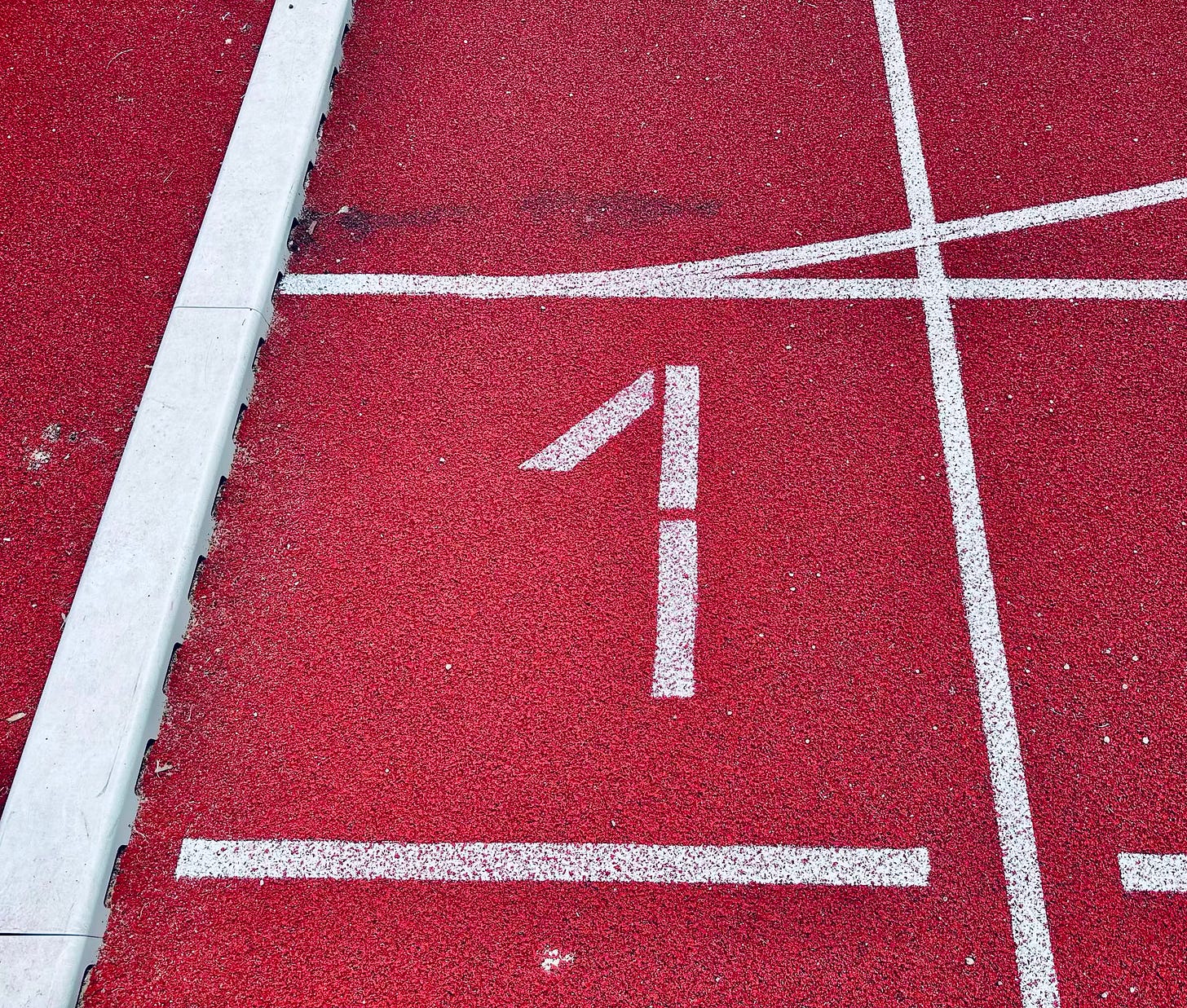 The number one painted on a running track, symbolizing one year of showing up and not walking away. The number one painted on a running track, symbolizing one year of showing up and not walking away.