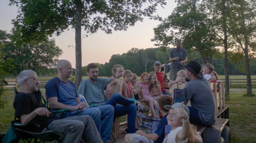 The dad's and their kids sitting on the makeshift hay wagon