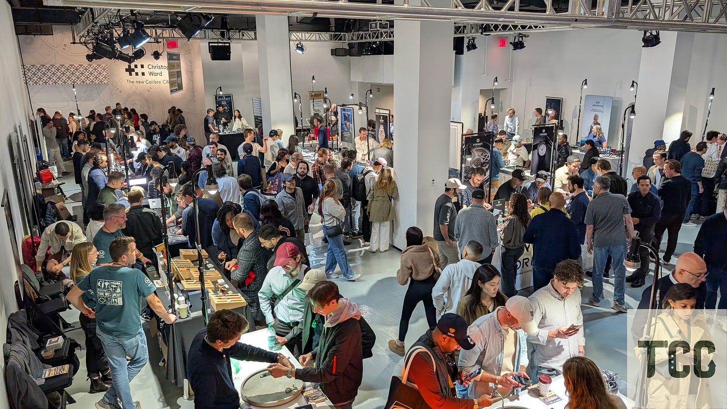 Overhead view of the ground-floor exhibition hall at Windup Watch Fair, showing densely packed booths and attendees. Brands like Christopher Ward anchor the space. The room is filled with display lighting, wristwatch try-ons, and active conversations.