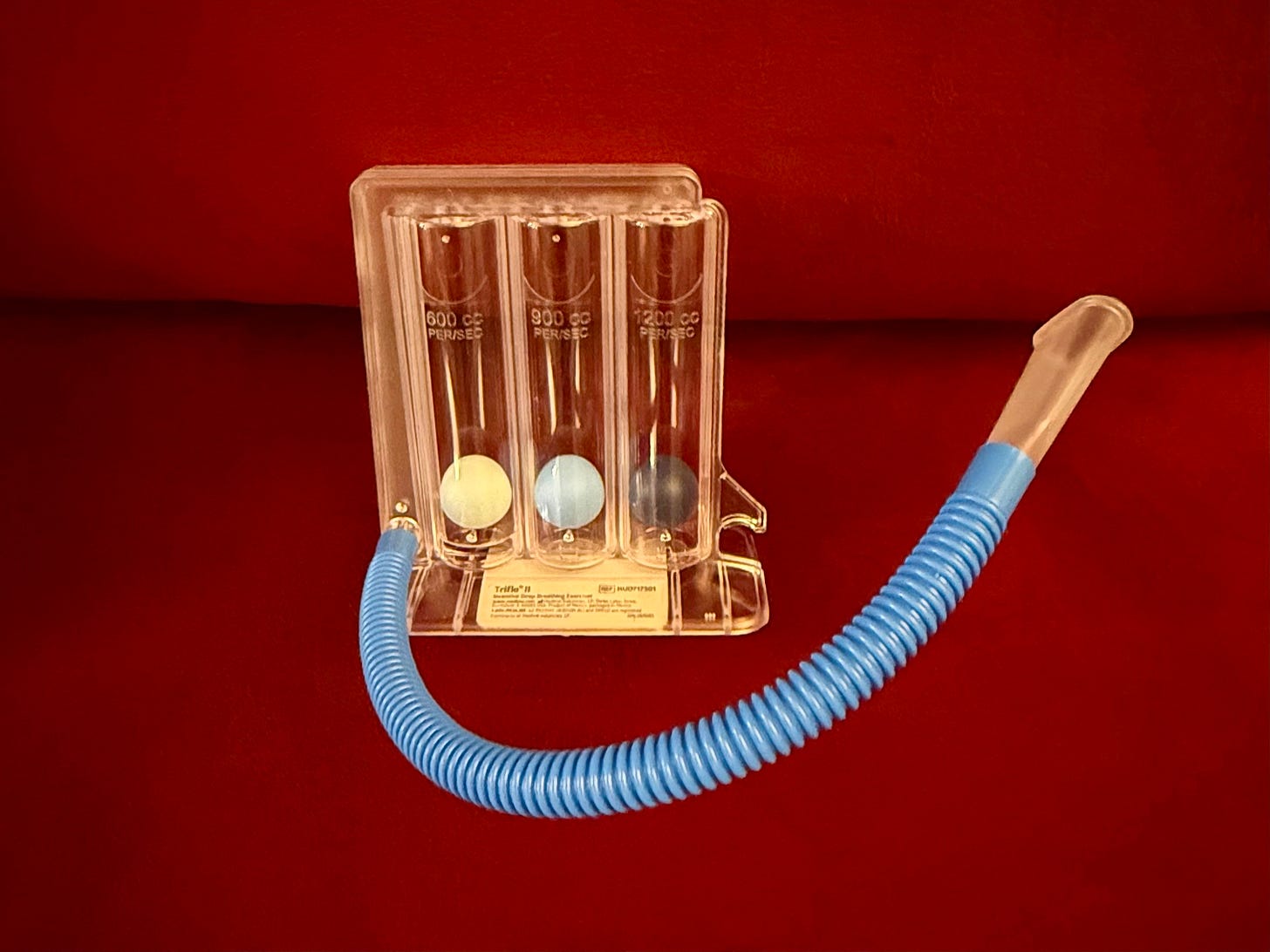 Photo of a spirometer, a transparent plastic box holding three colored plastic balls and attached to a tube for inhaing Photo of a spirometer, a transparent plastic box holding three colored plastic balls and attached to a tube for inhaing