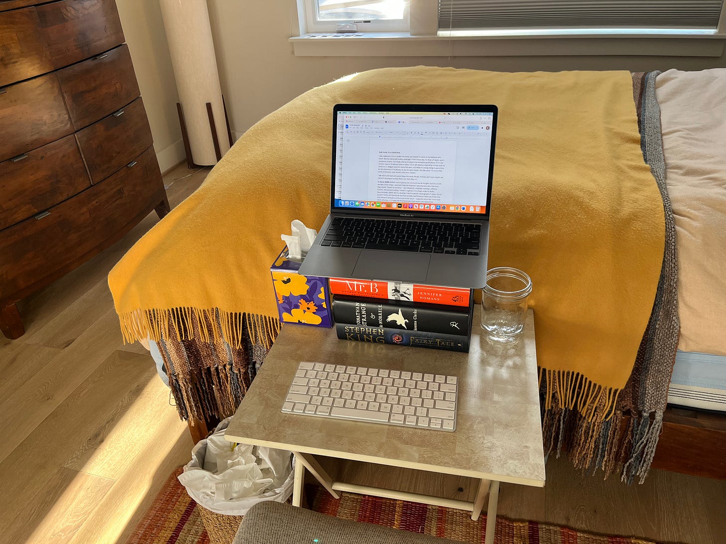 A card table set up as a makeshift desk, with a stack of books propping up a laptop.