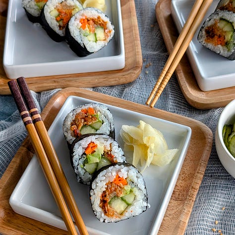 An assortment of futomaki sushi rolls, each filled with a variety of colorful ingredients like vegetables, pickled items, and vegan tamagoyaki. 