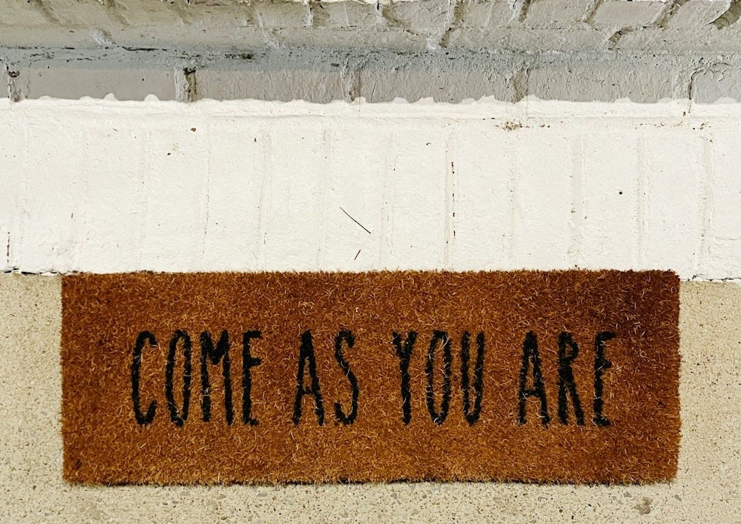 person standing on brown and black welcome printed floor mat