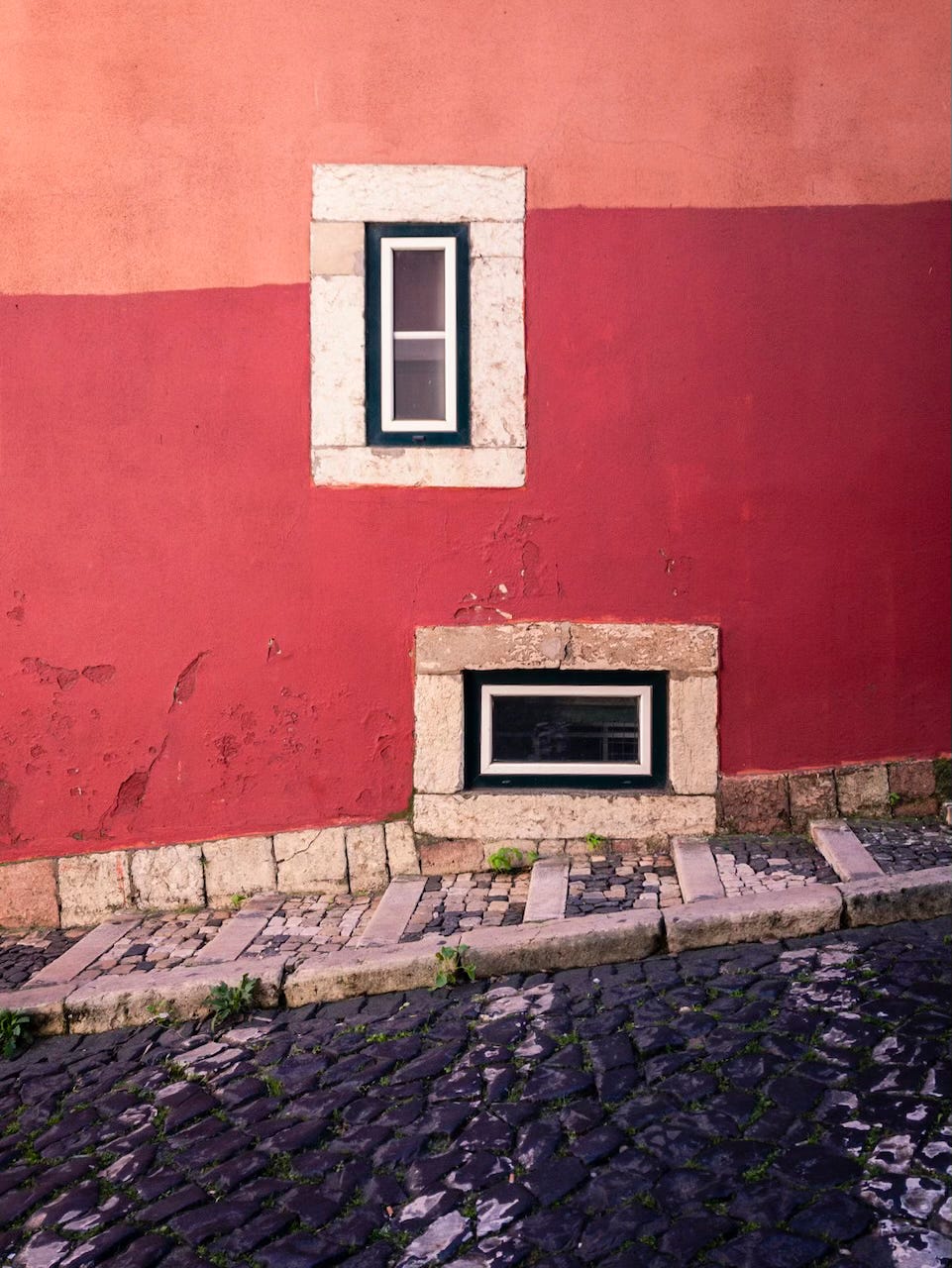 two windows and hues of red on a façade in Lisbon