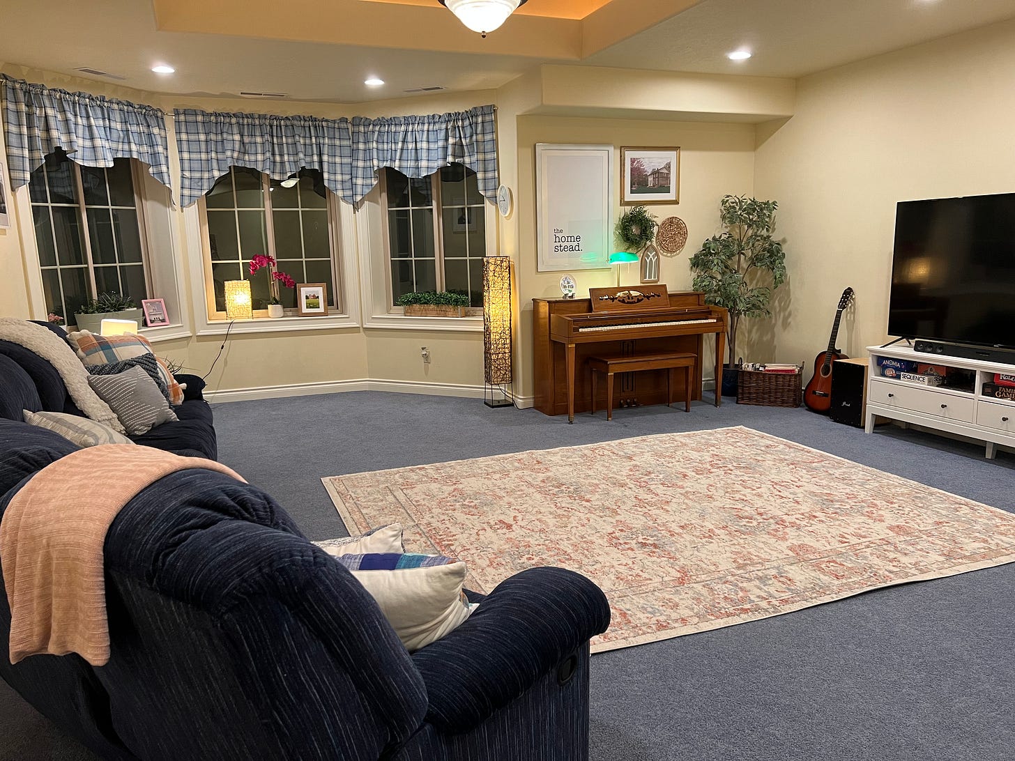 A living room with couches, a rug, a piano, and a TV.