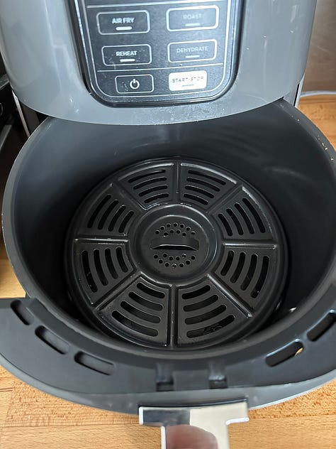 open ninja air fryer; open Cosori airfryer; two air fryer baskets side by side.