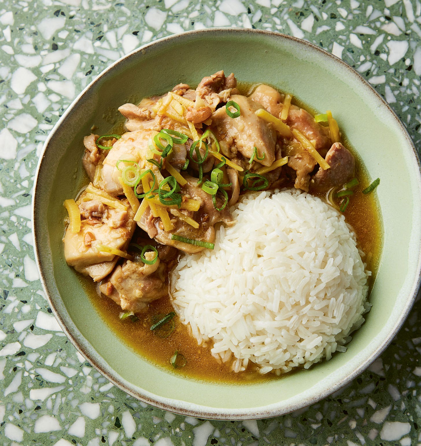 Bowl of gingery chicken on green counter.
