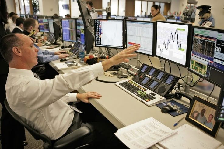 This may contain: a man sitting at a desk in front of multiple computer monitors