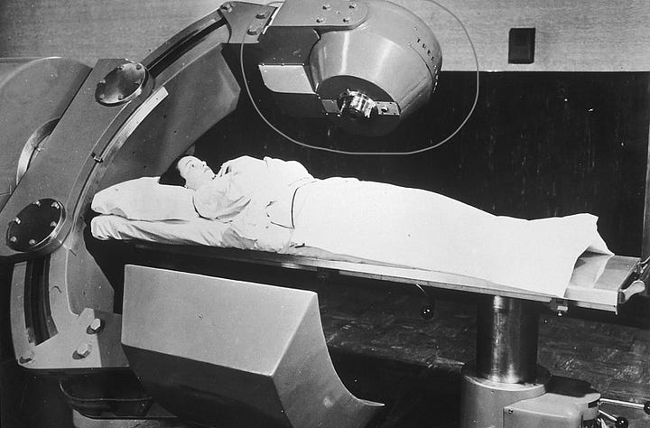 Left sie: black an white photo of a woman laying wrapped in white sheets underneath a large metal arm with a metal capsule above her. right side, the detail of the metal capsule which contain the radioactive material to treat cancers