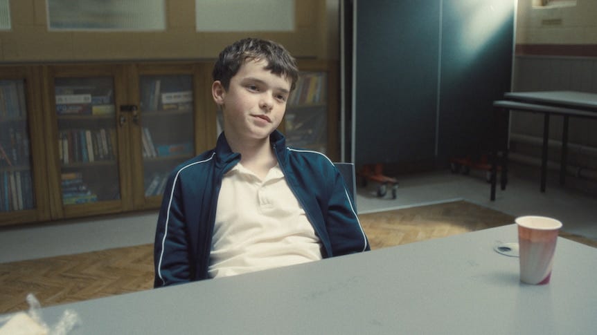Owen Cooper leans back in a chair and smirks while acting in Adolescence. Owen Cooper leans back in a chair and smirks while acting in Adolescence.