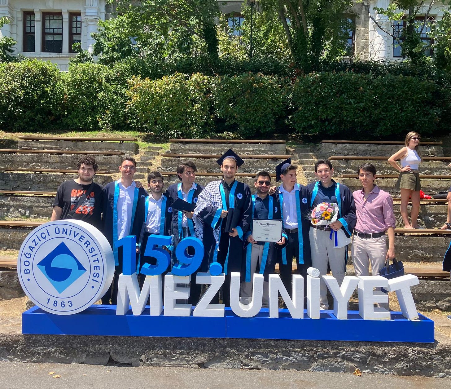 Boğaziçi'nde mezuniyet pozu veren bir grup öğrenci. Önde 159. mezuniyet yazıyor. Ortadaki öğrenci bir kefiye takmış.