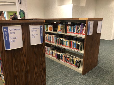 Adults and children in a public library borwworing, browsing, returning  books 