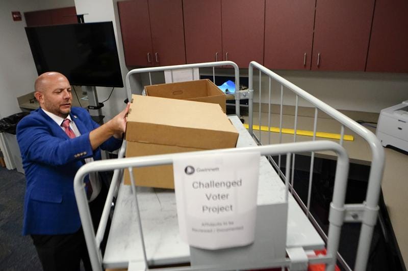 Gwinnett County elections supervisor Zach Manifold looks over boxes of voter challenges on Thursday, Sept. 15, 2022, in Lawrenceville, Ga. Manifold estimated his office has a month to log and research the challenges, before mail ballots go out for the November elections. “It is a tight window to get everything done,” he said. (AP Photo/John Bazemore)