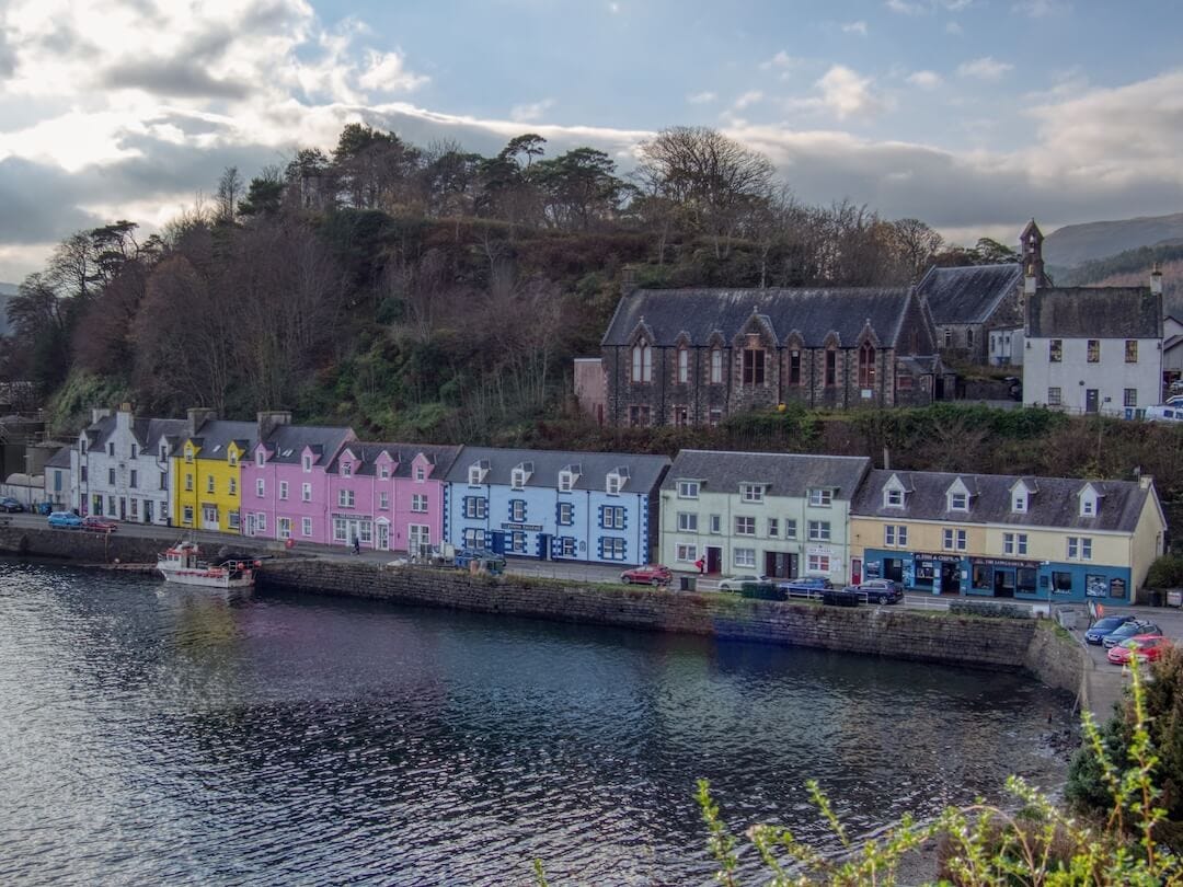 A row of pastel coloured buildings overlooking a walled harbour