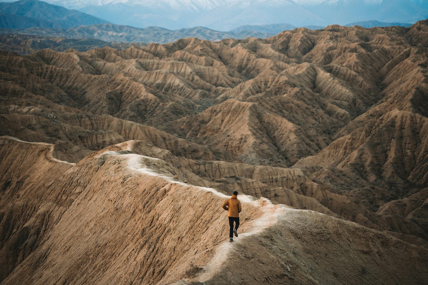 Image of a man walking a trail in Kyrgyzstan by Spenser Sembrat on Unsplash.