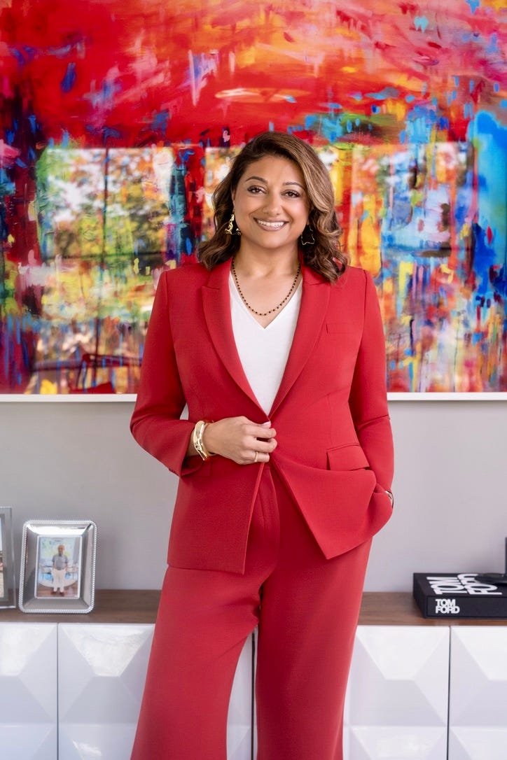 Deepali standing and posing in a power red suit