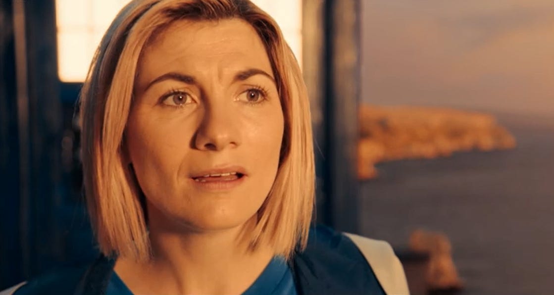 Close-up of a youngish white woman with shoulder-length blonde hair (Jodie Whittaker). Behind her is the TARDIS and a Dorset coastal seascape. Close-up of a youngish white woman with shoulder-length blonde hair (Jodie Whittaker). Behind her is the TARDIS and a Dorset coastal seascape.