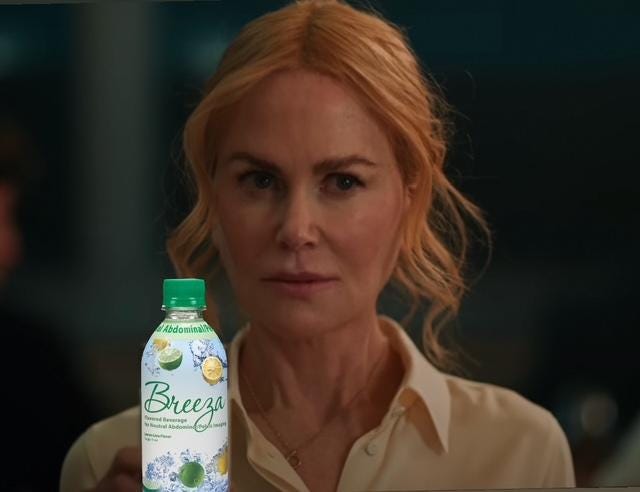 Nicole Kidman in BABYGIRL: shoulders-up shot of Kidman looking curiously toward the camera and holding a drink. In the film, it's a glass of milk, but this image has been poorly photoshopped to replace her glass with a plastic green bottle of Breeza Lemon Lime Flavored Beverage for Pelvic/Abdominal Imaging (contrast fluid). The bottle is covered with images of refreshing splashes of liquid and halves of various citrus fruit.