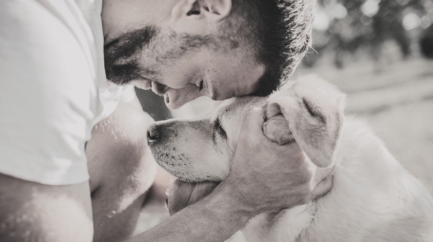 profile of man resting head on a large dogs head
