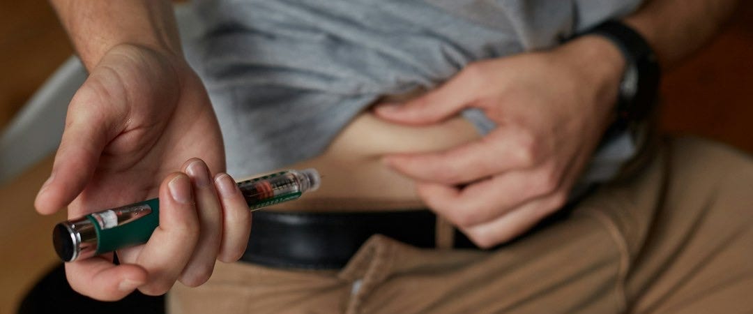 a person injecting insulin into stomach for diabetes management