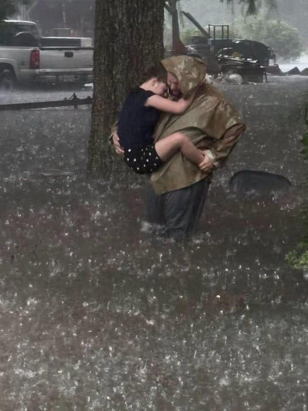 A father carries his child through floodwaters in Simmesport during the storm.