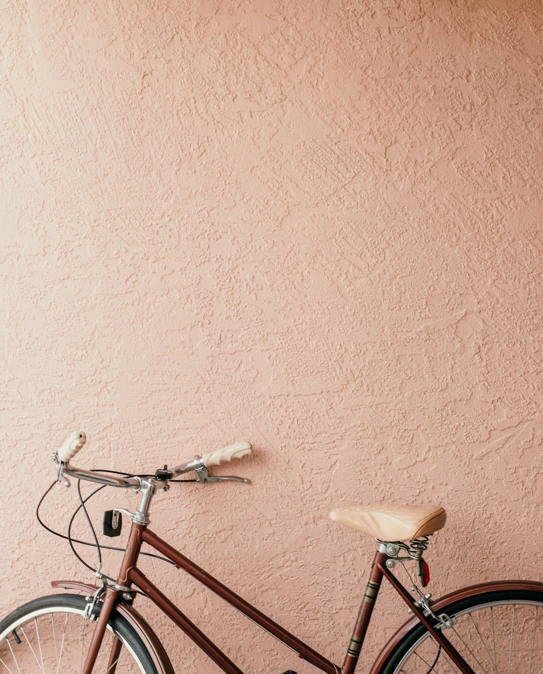 white city bike beside pink wall
