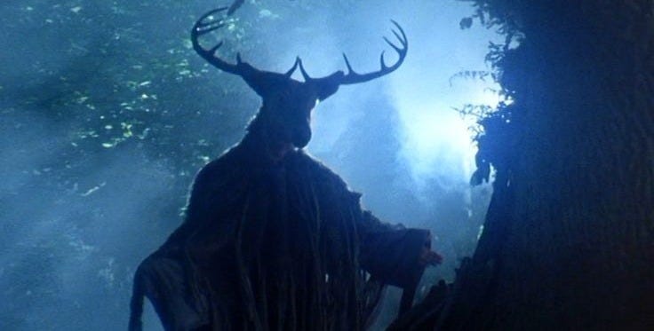 This may contain: a man standing next to a tree with antlers on his head in the woods This may contain: a man standing next to a tree with antlers on his head in the woods