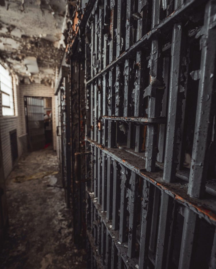 A prison cell in a hallway

Description automatically generated