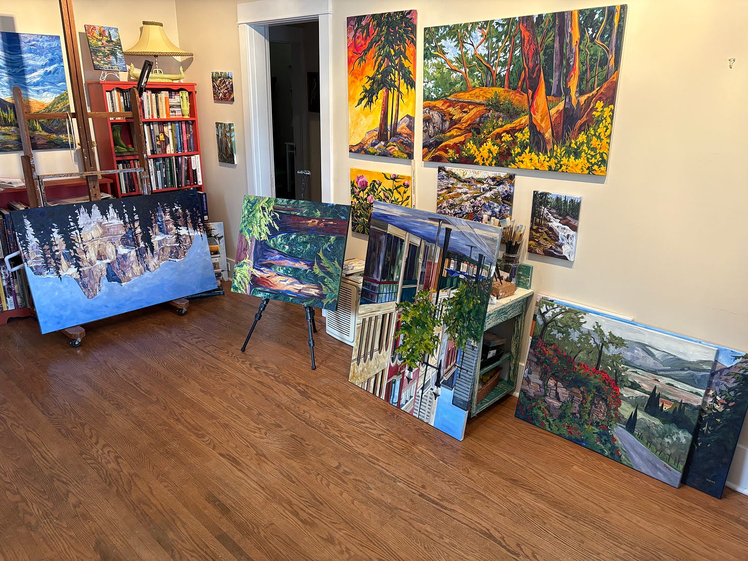 a view of Caprice's Studio with oil paintings upside down with wet paint on their edges.  Some paintings are on the wall.