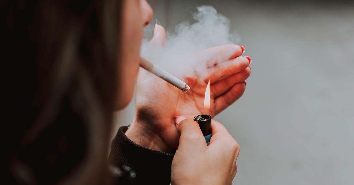 Imagem de perfil de um rosto feminino acendendo um cigarro com seu isqueiro Imagem de perfil de um rosto feminino acendendo um cigarro com seu isqueiro