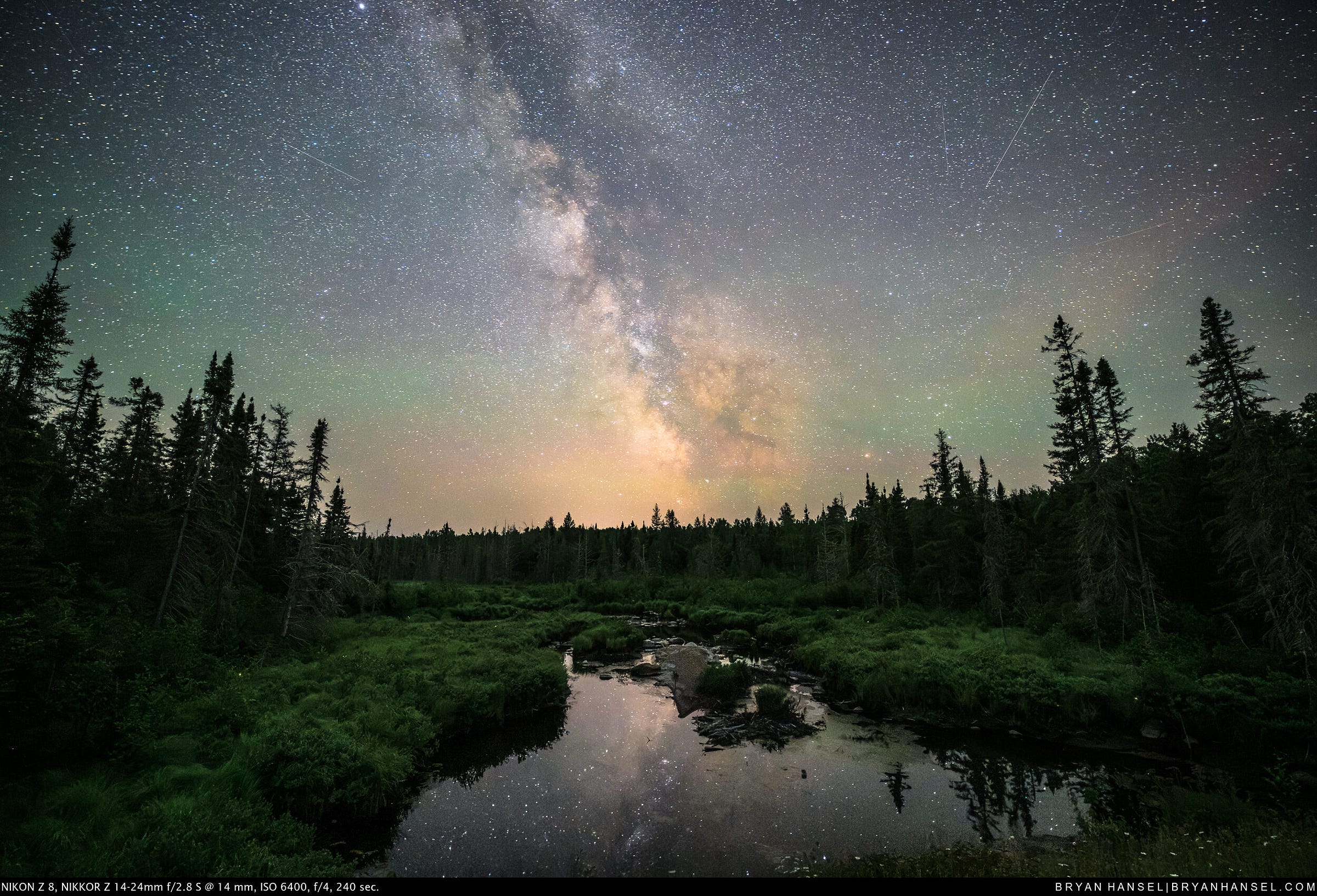 The Milky Way over a small creek. Stars reflect in the creek.