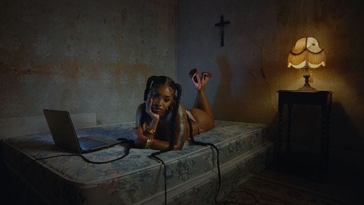This may contain: a woman laying on top of a bed with a laptop computer in her hand and a lamp next to her