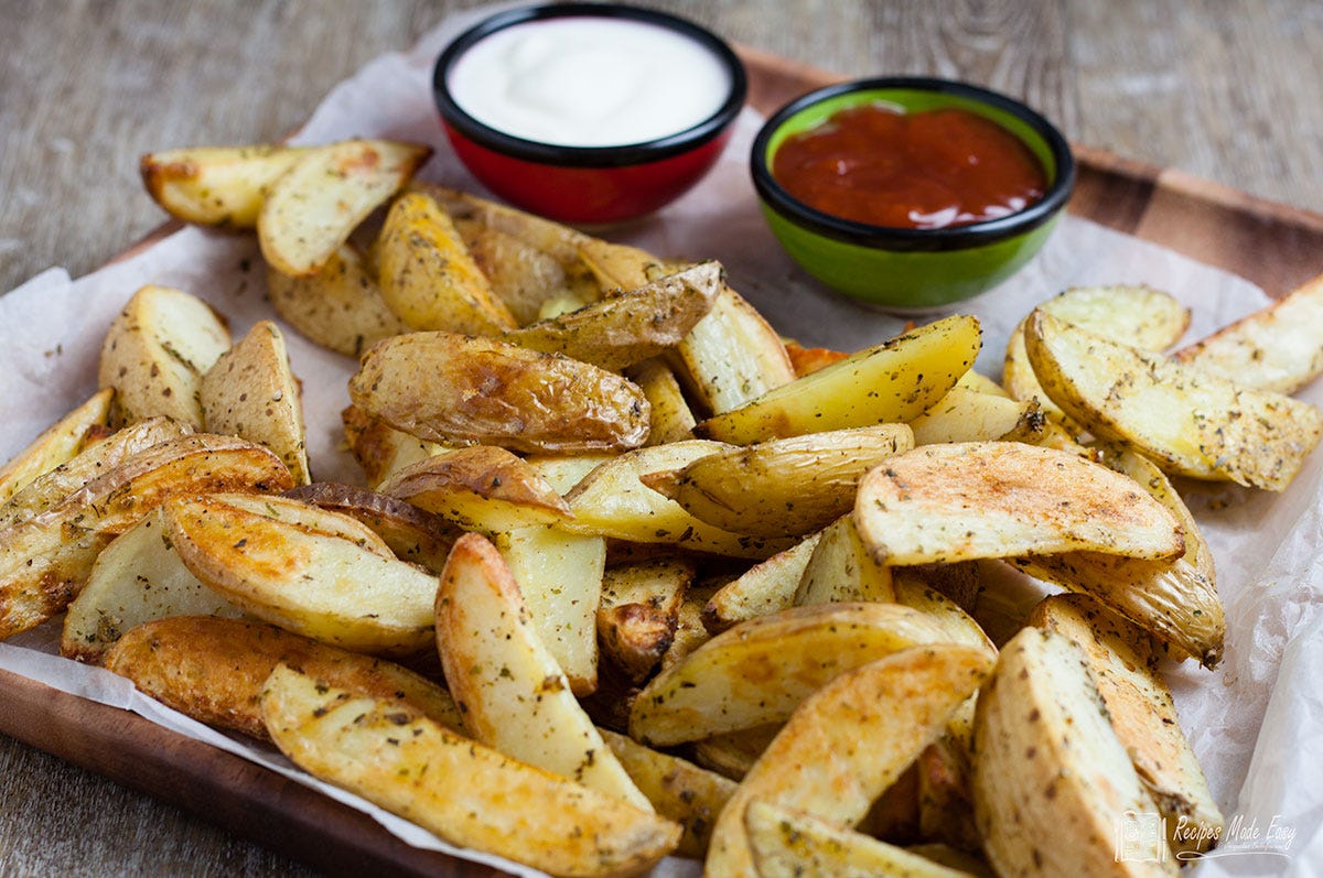 paper lined wooden tray with oven wedges and two dips.