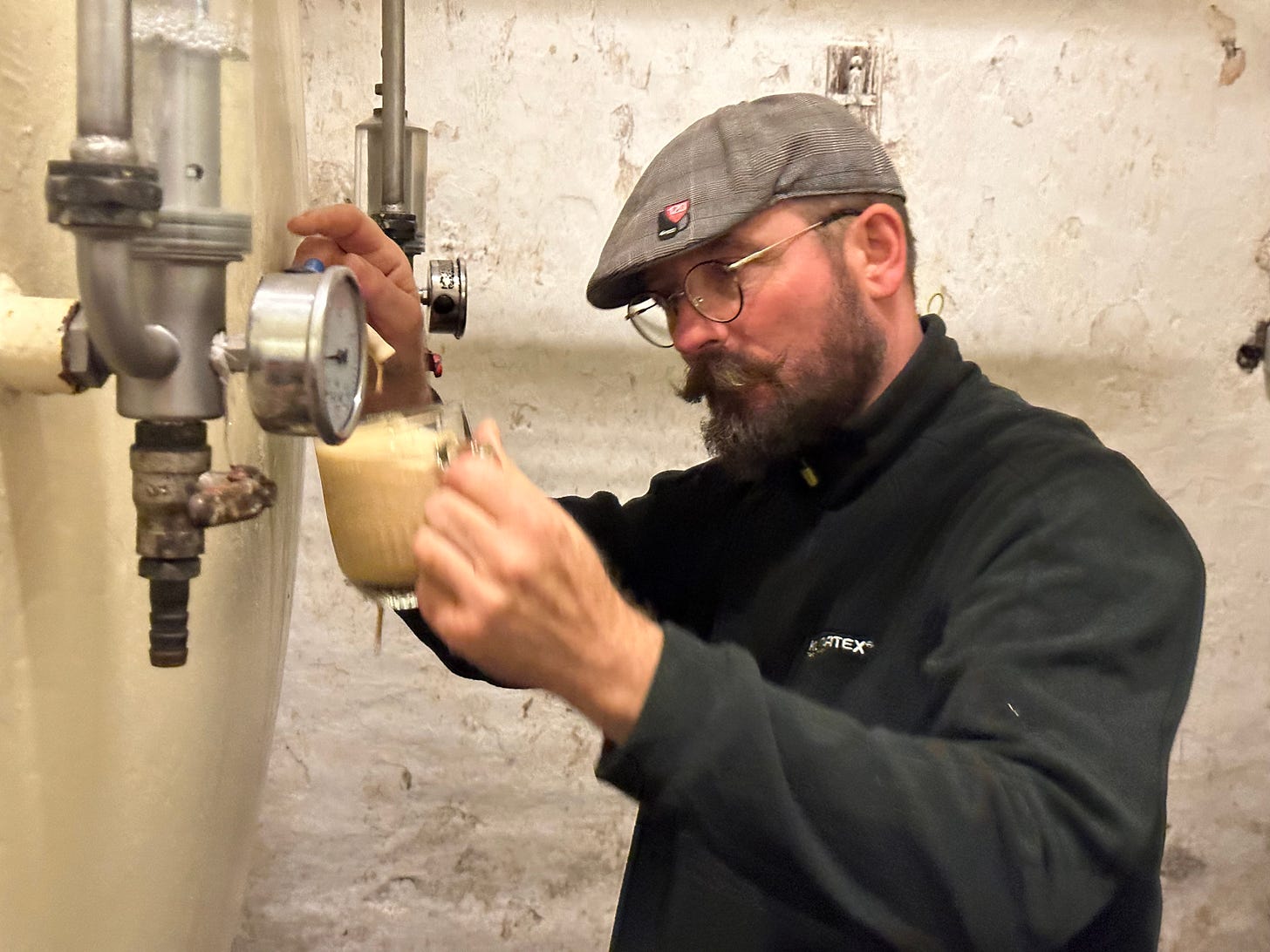 A Czech brewer pouring beer from the tank in the Budvar cellars