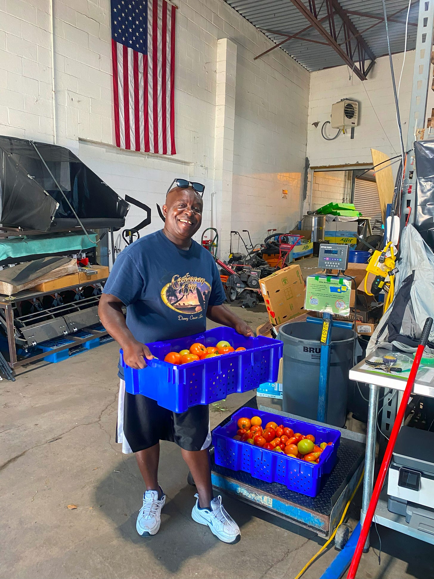 A man holding a box of tomatoes in a warehouse.