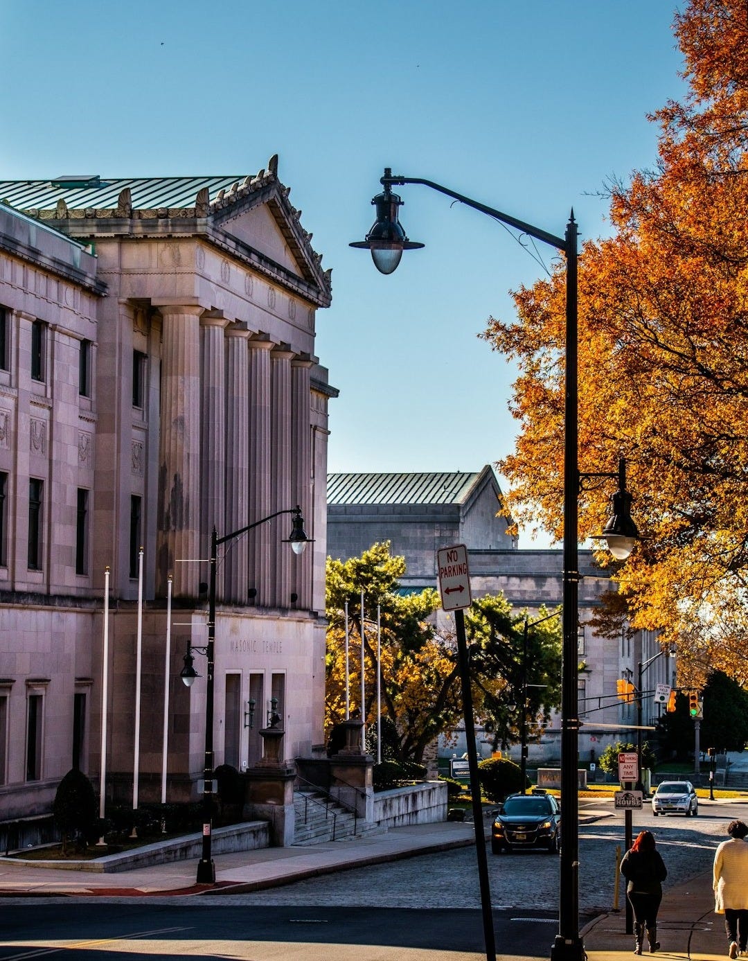 two people walking down a street next to a tall building in Trenton, New Jersey. two people walking down a street next to a tall building in Trenton, New Jersey.